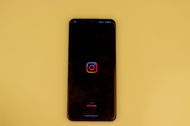 شعار Instagram على شاشة سوداء لهاتف ذكي على خلفية صفراء صامتة.