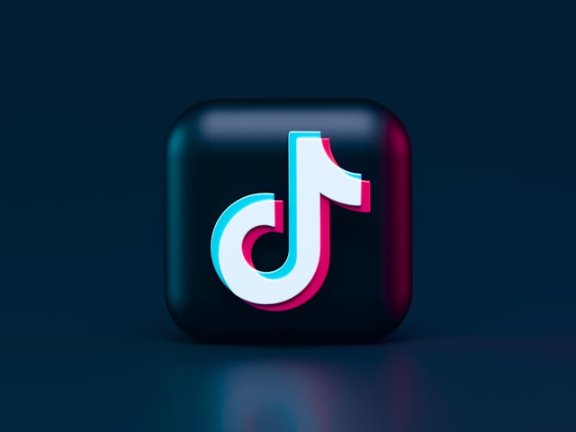 Vergrößertes TikTok-Logo vor einem dunkelblauen Hintergrund.