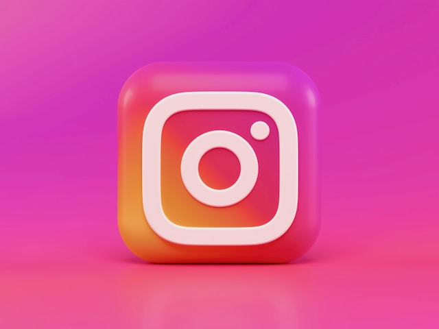 Vergrößertes Instagram-Logo vor einem pinkfarbenen Hintergrund.