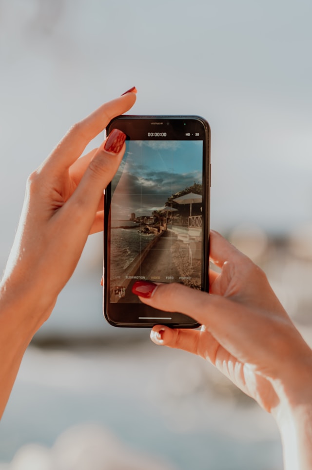 Eine Person filmt eine Landschaftsaufnahme mit ihrem Smartphone.