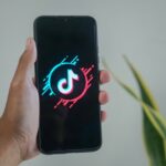 Eine Person hält ein Smartphone mit dem TikTok-Logo auf dem Bildschirm.