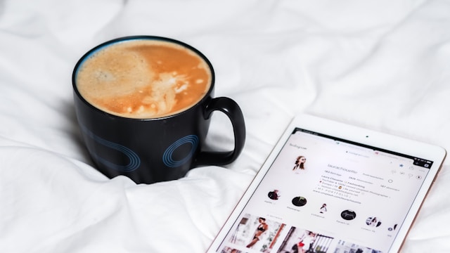 Eine Tasse Kaffee und ein Smartphone, das das Instagram-Profil von jemandem anzeigt.