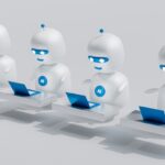 Eine Reihe von vier weißen Robotern, jeder mit einem Laptop.