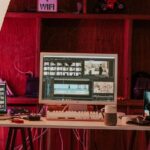 Ein Computer und zwei Laptops auf jeder Seite, auf denen Bearbeitungssoftware angezeigt wird.