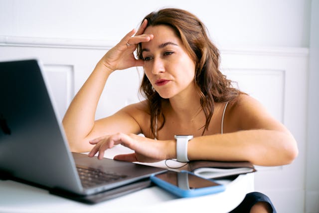 Eine Frau, die frustriert auf ihren Laptop schaut.