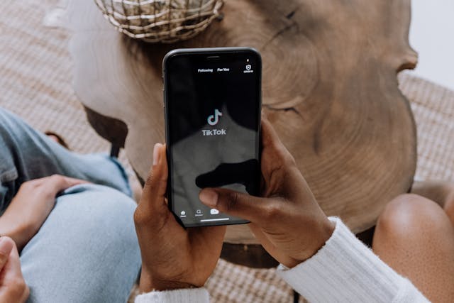 Eine Person hält ihr Smartphone in der Hand, während TikTok auf dem Bildschirm geladen wird. 
