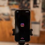 Ein an einem Stativ befestigtes Smartphone, auf dessen Bildschirm Instagram geladen wird.