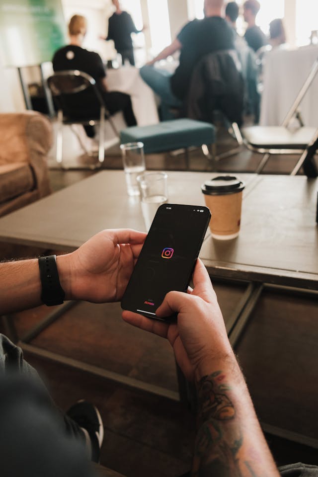 Eine Person hält ein Smartphone in der Hand, auf dessen Bildschirm Instagram geladen wird.