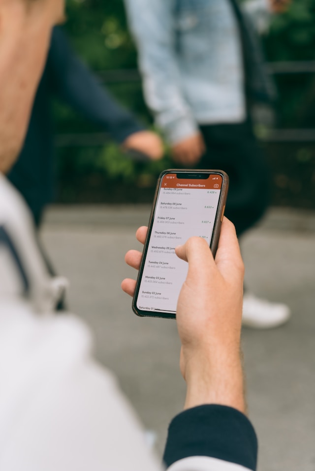 Eine Person hält ein Smartphone in der Hand, auf dessen Bildschirm YouTube Analytics angezeigt wird.