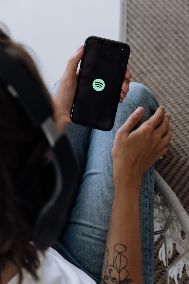 Eine Person, die ein Smartphone in der Hand hält und auf dem Bildschirm Spotify lädt.