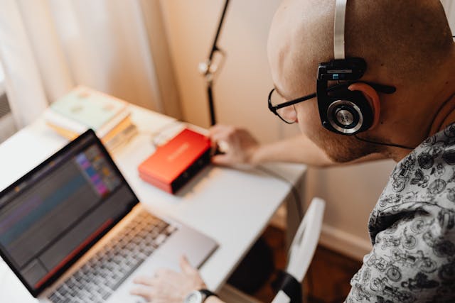 Eine Person, die Musik auf ihrem Laptop bearbeitet.