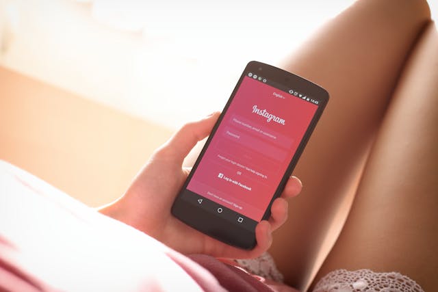 Una mujer sostiene un smartphone negro con una página de acceso a Instagram.