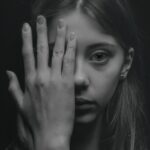 Una mujer de aspecto espantoso mirando a través de sus dedos.