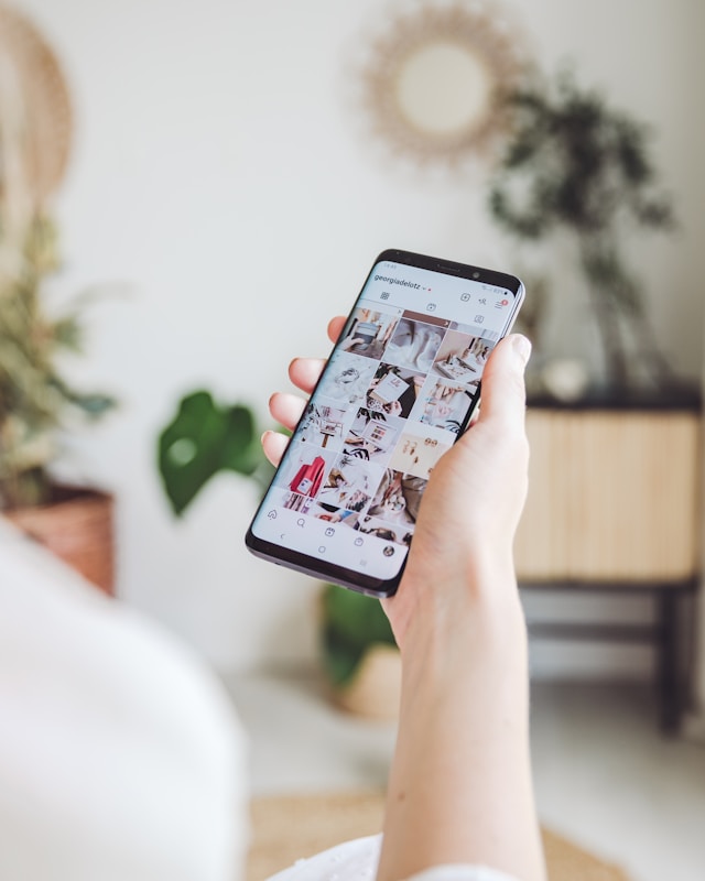 Una persona con un smartphone en la mano y un feed de Instagram en él. 