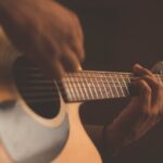 Una persona rasgueando la guitarra.