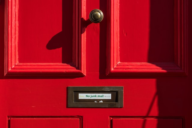 Una imagen de una puerta roja con una nota que dice: "Prohibido el correo basura".