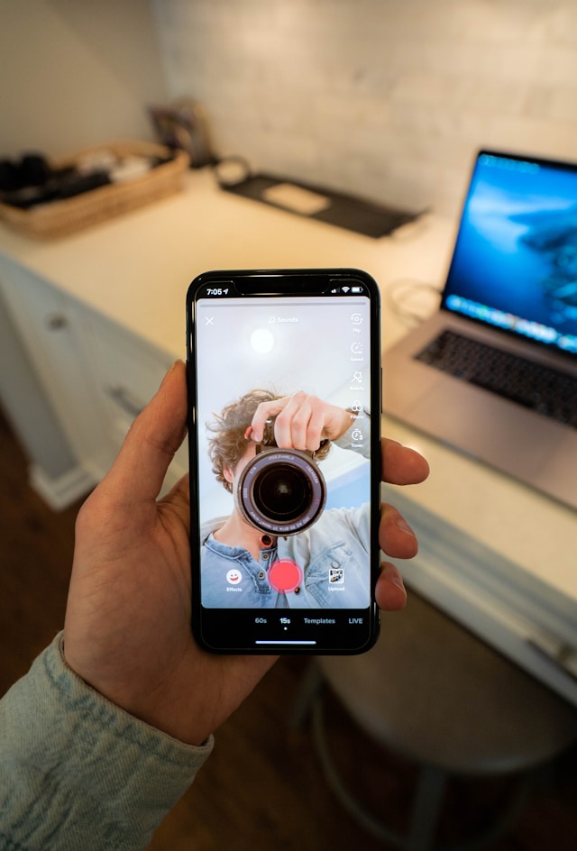 Una persona con un teléfono inteligente mostrando a otra con una cámara.