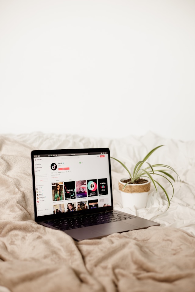 Un portátil encima de una cama mostrando la cuenta de TikTok en su página web.