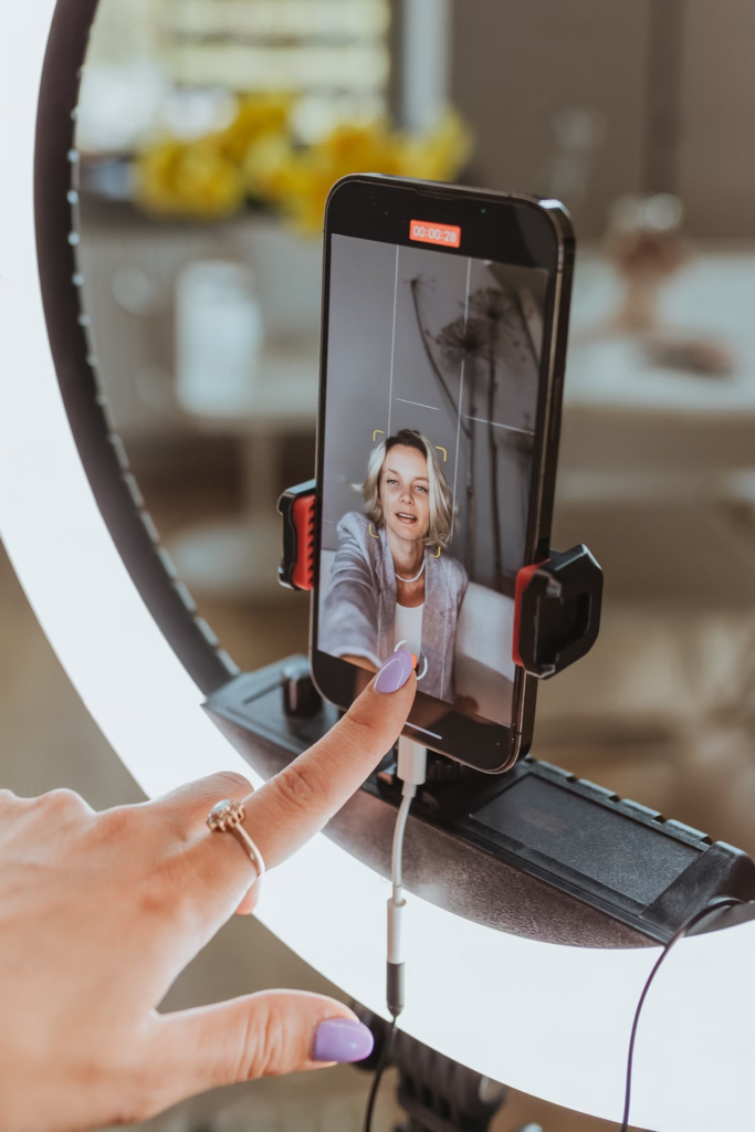 Una mujer grabando un vídeo TikTok con su smartphone montado en un anillo luminoso.