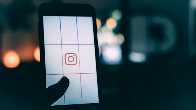 Una persona toca la pantalla de un smartphone con el logotipo de Instagram colocado en una cuadrícula.
