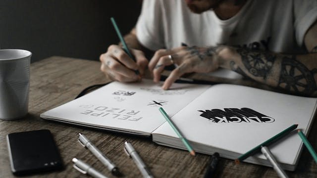Una persona dibuja diferentes tipos de letra en un cuaderno de bocetos.