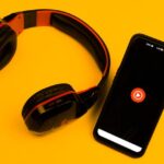 Unos auriculares junto a un smartphone cargando YouTube.