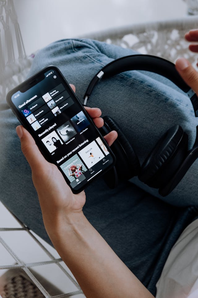 Una persona con un smartphone en la mano y la información de Spotify en la pantalla.
