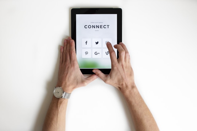 Une personne utilisant un onglet noir avec l'option de se connecter à divers canaux de médias sociaux.