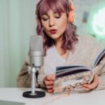Une personne qui parle dans un microphone tout en lisant un livre.