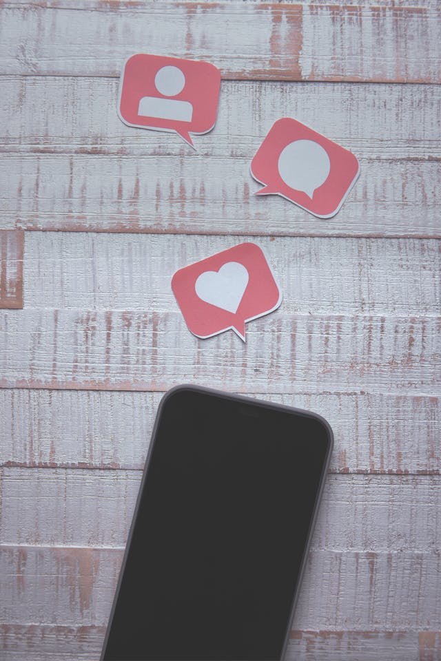 Un téléphone à côté de graphiques représentant des likes, des commentaires et des followers.