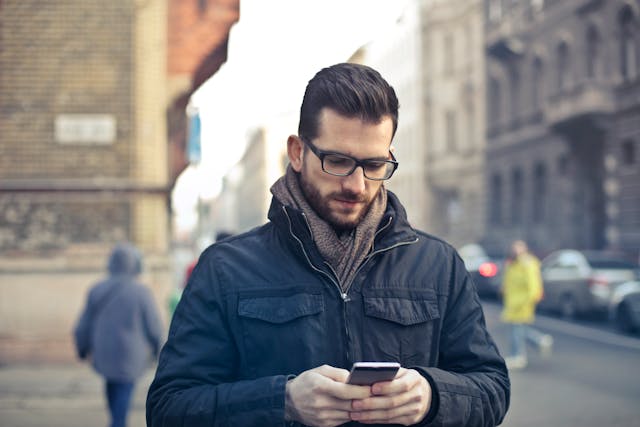 Une personne qui regarde son téléphone d'un air pensif.