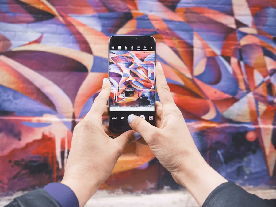 Une personne utilise un smartphone pour prendre une photo d'un mur graffité.