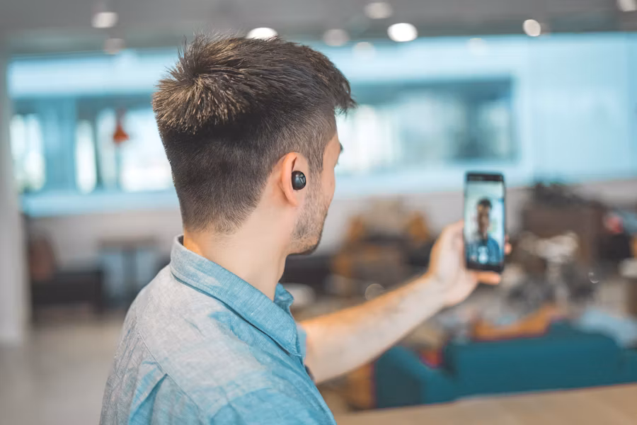 Un homme tenant un smartphone d'un bras tout en prenant un selfie.