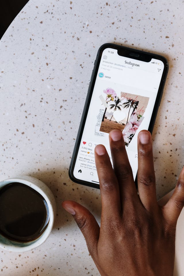 Un smartphone posé sur une table et une personne faisant défiler Instagram.