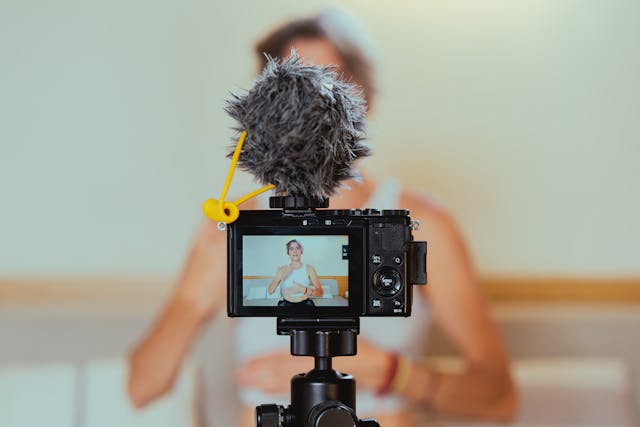Photo en contre-plongée d'une caméra vidéo enregistrant une femme.