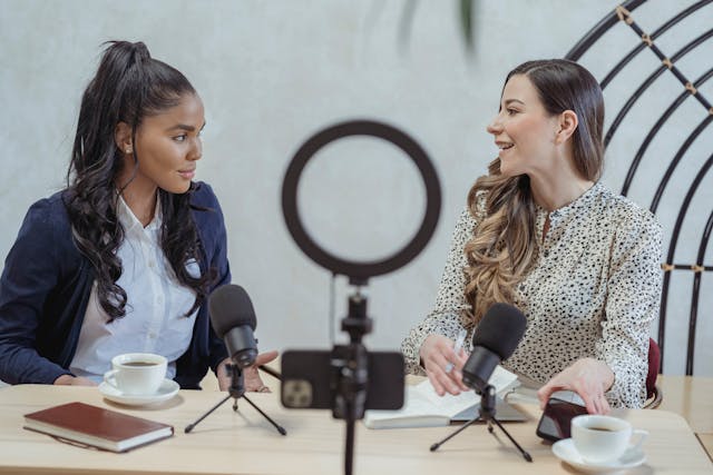 Un influenceur souriant interviewant une invitée et enregistrant une vidéo.