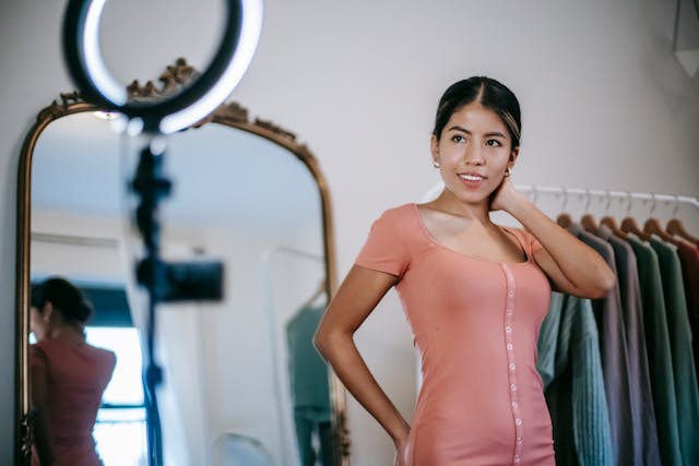 Une influenceuse souriante qui s'enregistre en montrant sa robe.