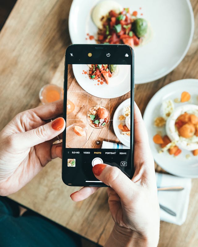 Une femme prenant une photo de nourriture avec son smartphone.