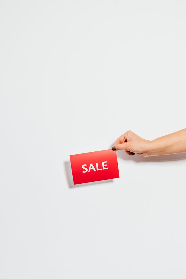 Une personne tenant une carte de vente rouge.