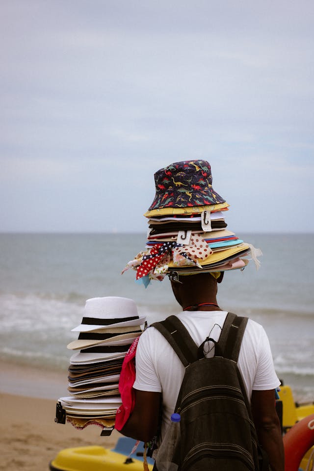Un homme qui vend des chapeaux sur la plage.
