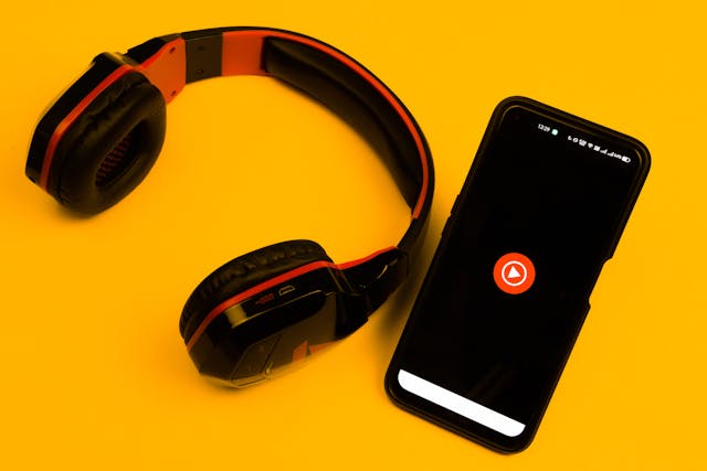 Une paire d'écouteurs à côté d'un smartphone chargeant YouTube.