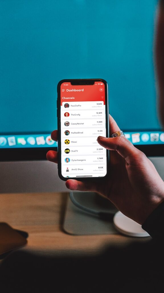 Une personne tenant un smartphone à la main avec le tableau de bord de YouTube affiché à l'écran.