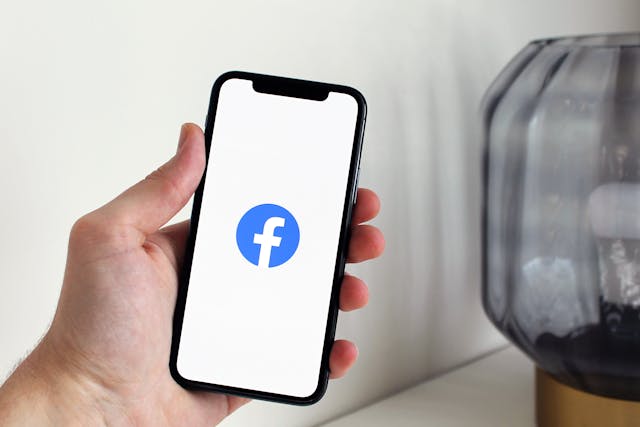 Une personne tenant un téléphone à la main avec Facebook chargé sur l'écran.
