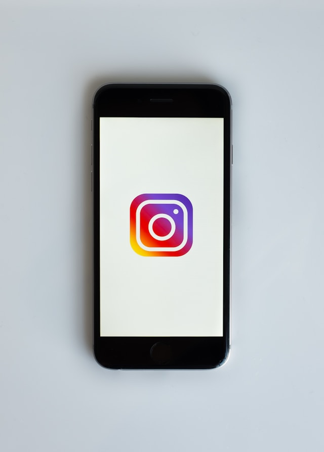 Il logo di Instagram viene mostrato sullo schermo di uno smartphone con uno sfondo bianco. 