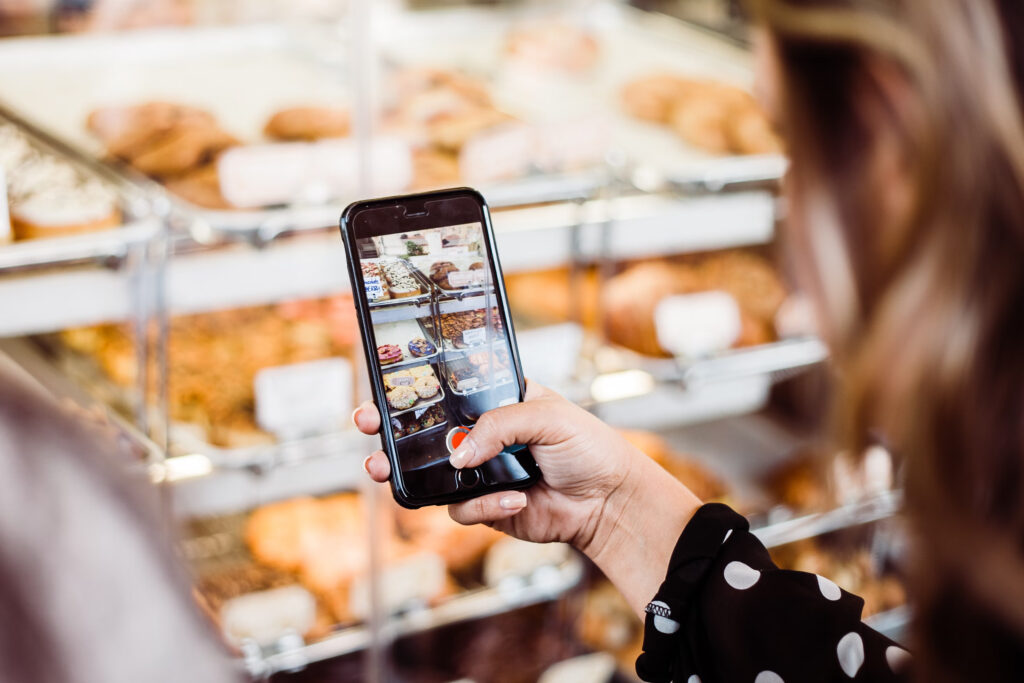 Una persona tiene in mano uno smartphone e riprende il cibo in una panetteria.