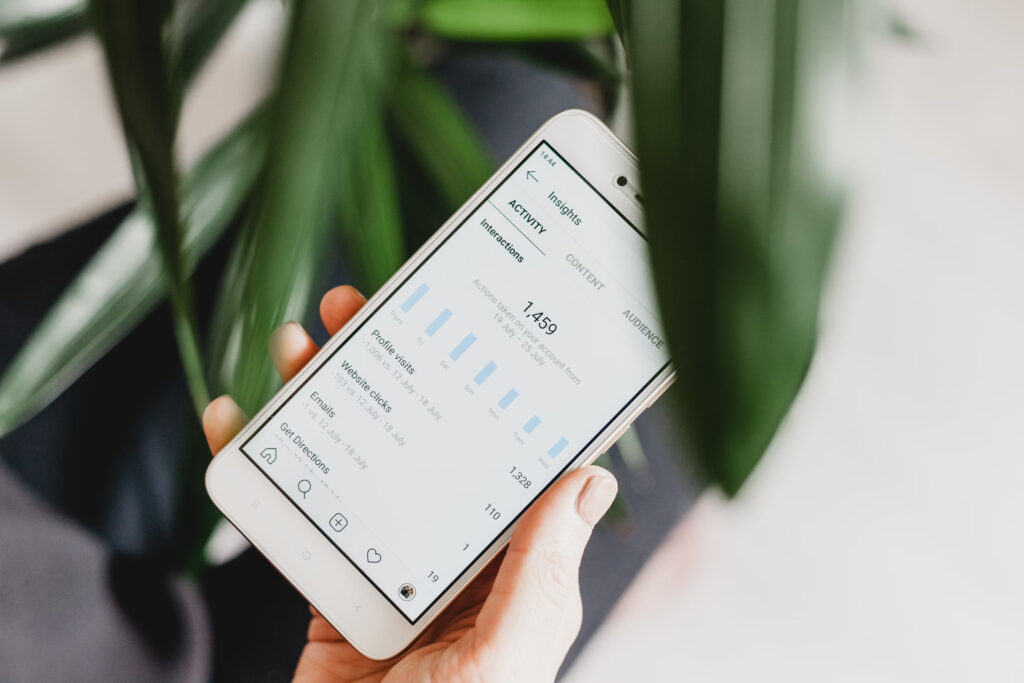 Uno smartphone mostra gli insight di Instagram con il numero 1.459 sopra un grafico a barre.