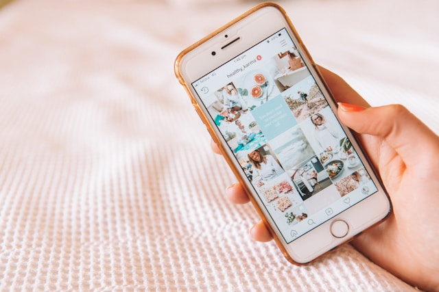 Una persona con in mano uno smartphone che visualizza un feed di Instagram. 