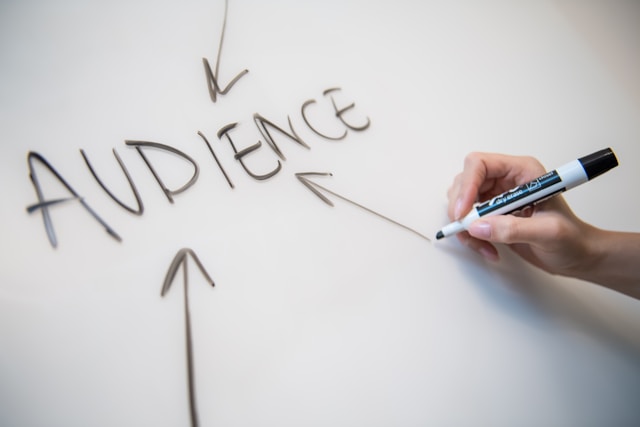 La frase "target audience" scritta su una lavagna con delle frecce che puntano verso di essa.