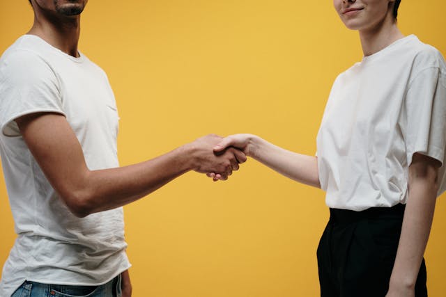 Due persone con magliette bianche che si stringono la mano.