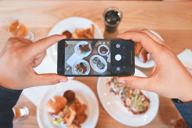 Una persona che fotografa diversi piatti con del cibo. 